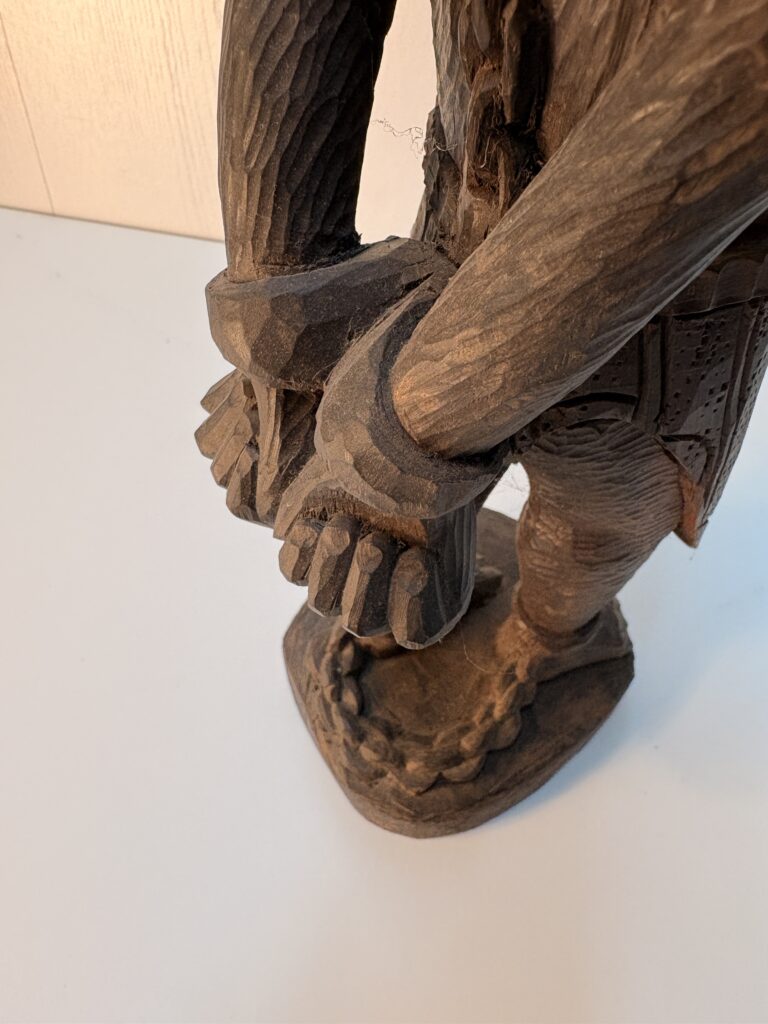 detail of restrained hands carved into a wooden figure