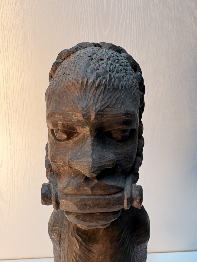 close-up of the face and covered mouth of an African wooden figure