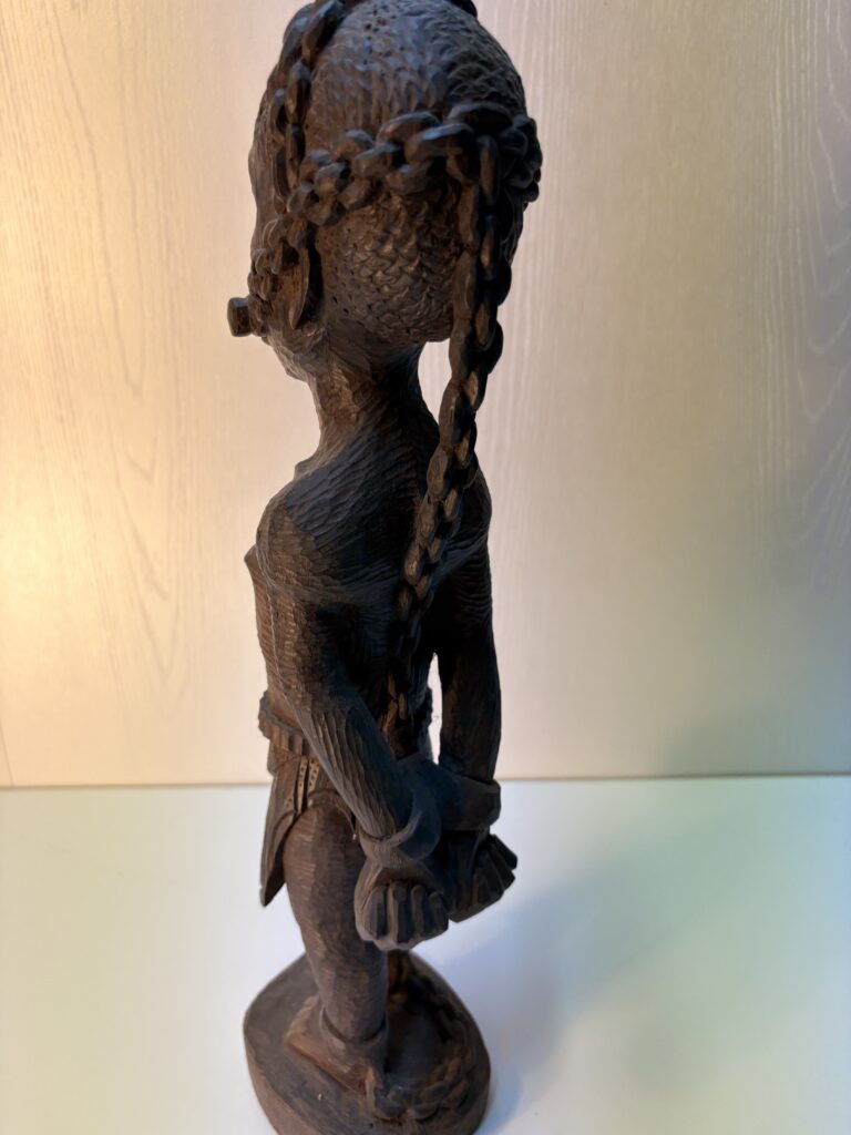side view of an upright wooden figure with hands restrained behind the body