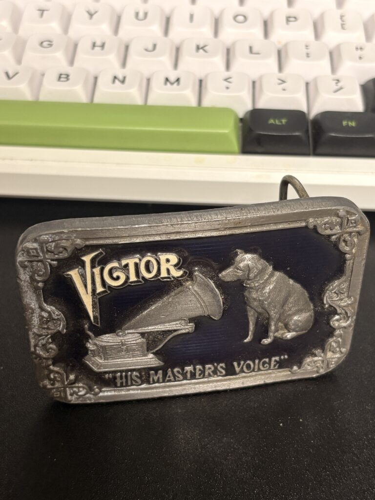 vintage Victor Nipper belt buckle beside a computer keyboard